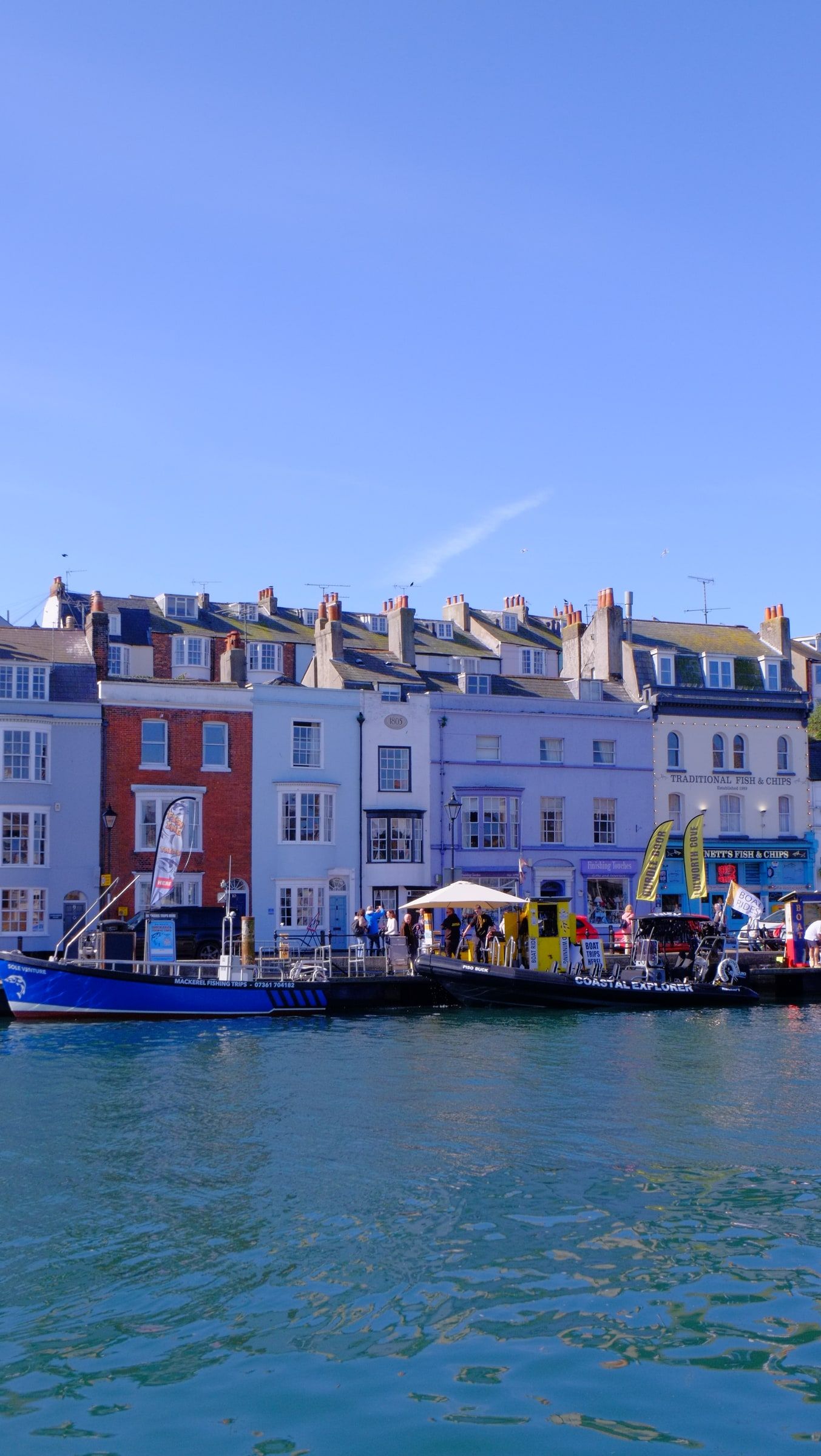 Brightly painted terraced houses along the quay, with boats and market stalls by the water