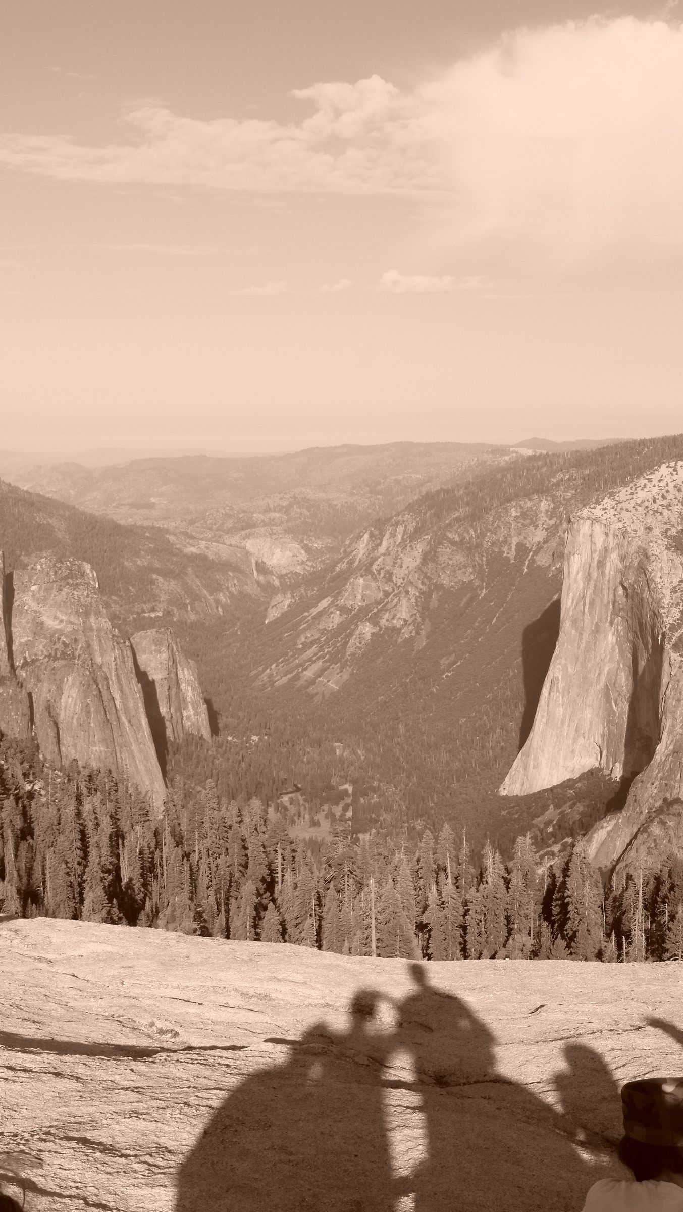 A sepia view down Yosemite Valley to El Capitan, the shadows of people cast across the granite in the foreground